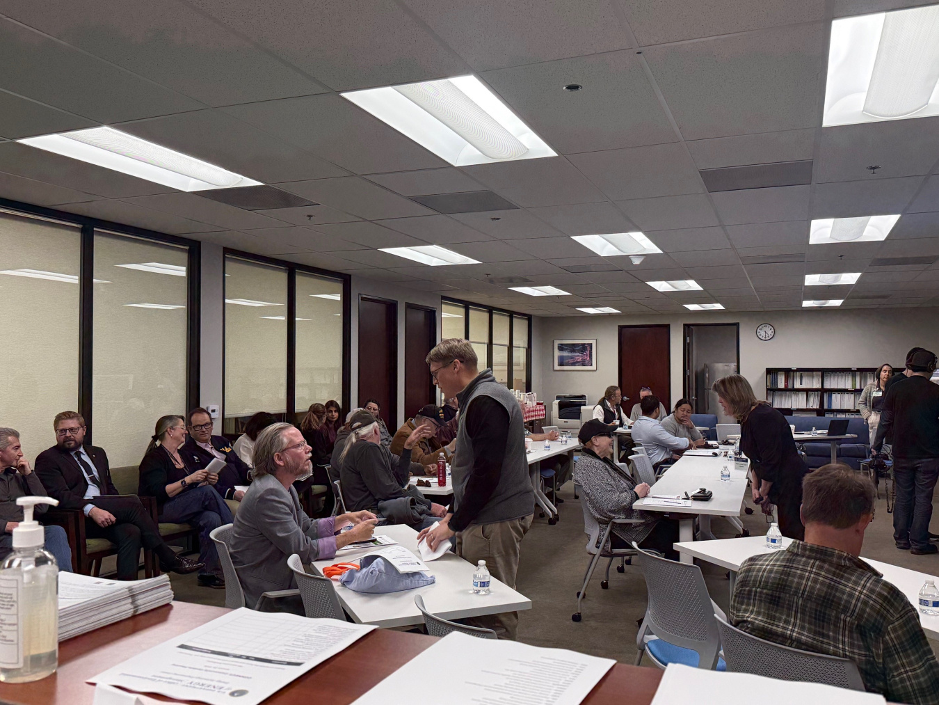 A room full of professionals, some sitting at tables and some standing in a room