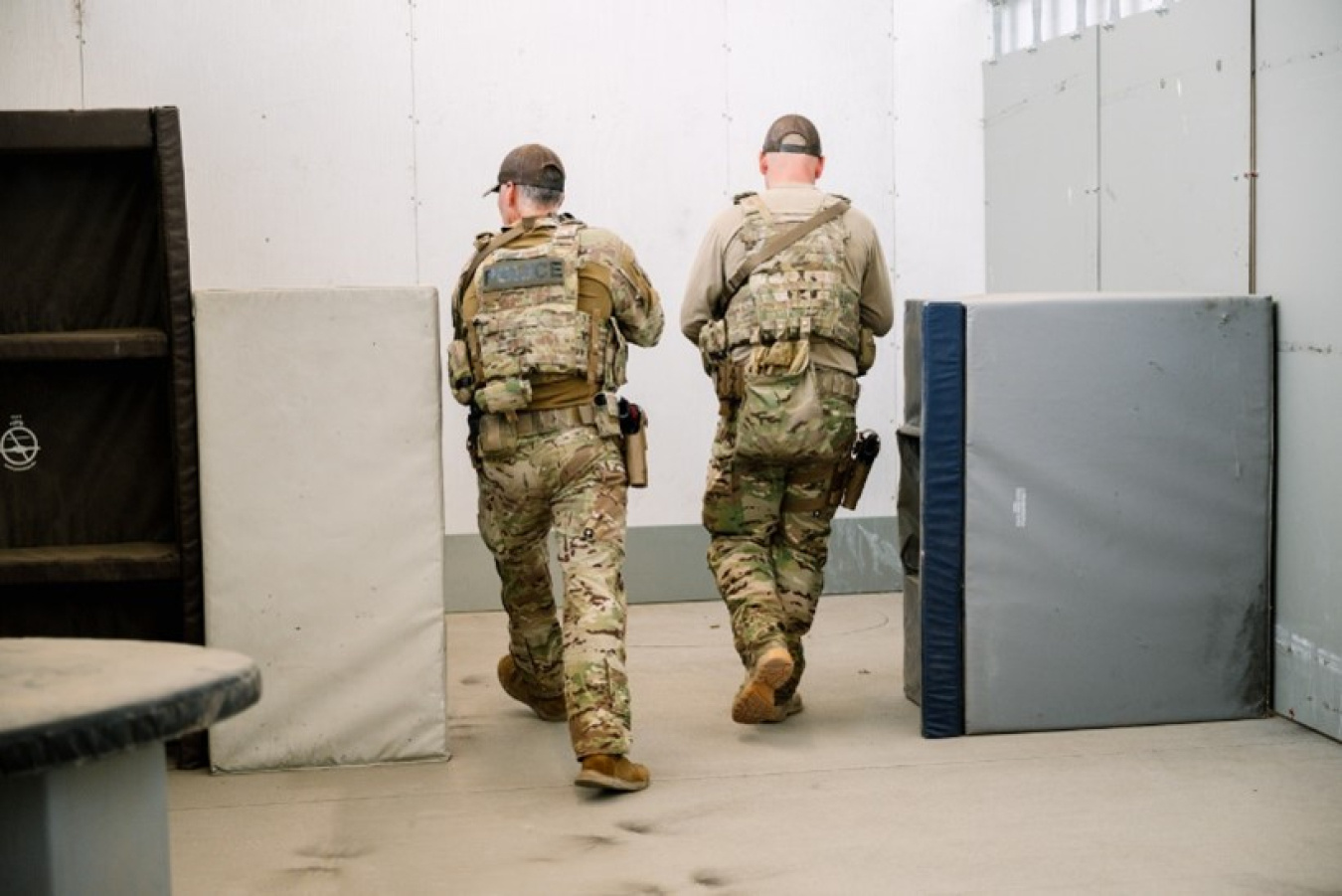 Two people in military uniforms walking through a building.