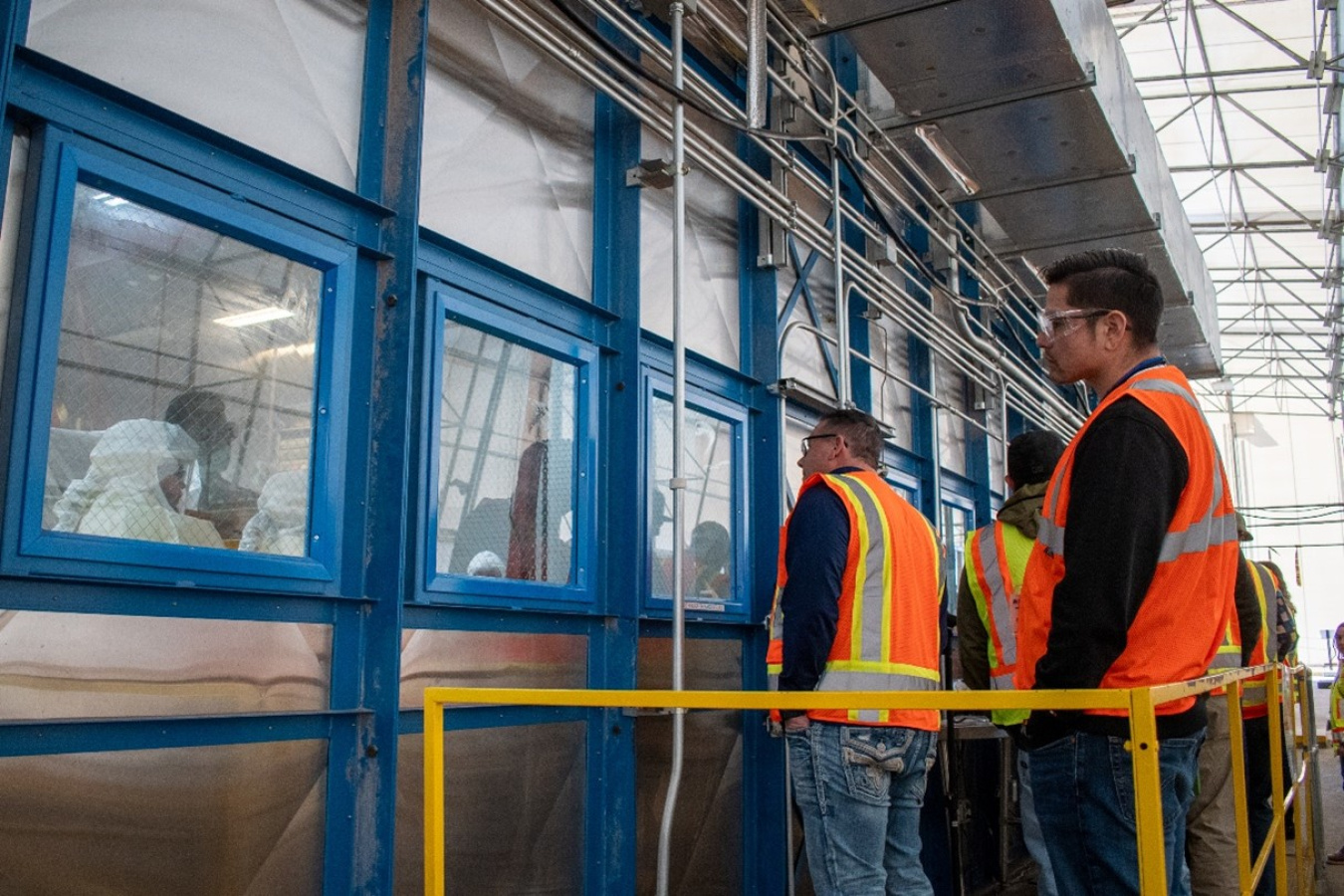 People in safety vests standing outside of a facility with blue trimmed windows