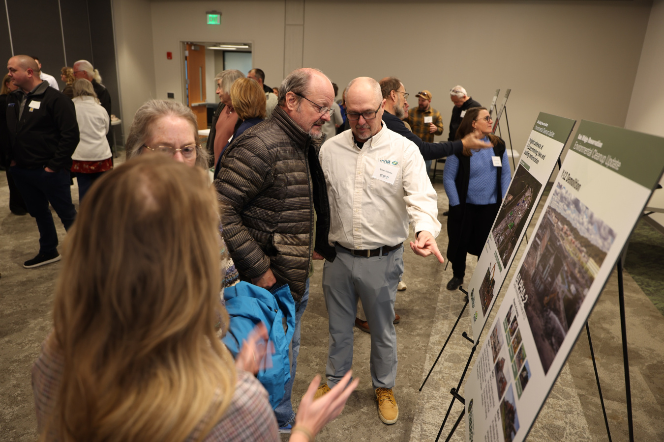 Groups of people looking at posters around a room at a public meeting