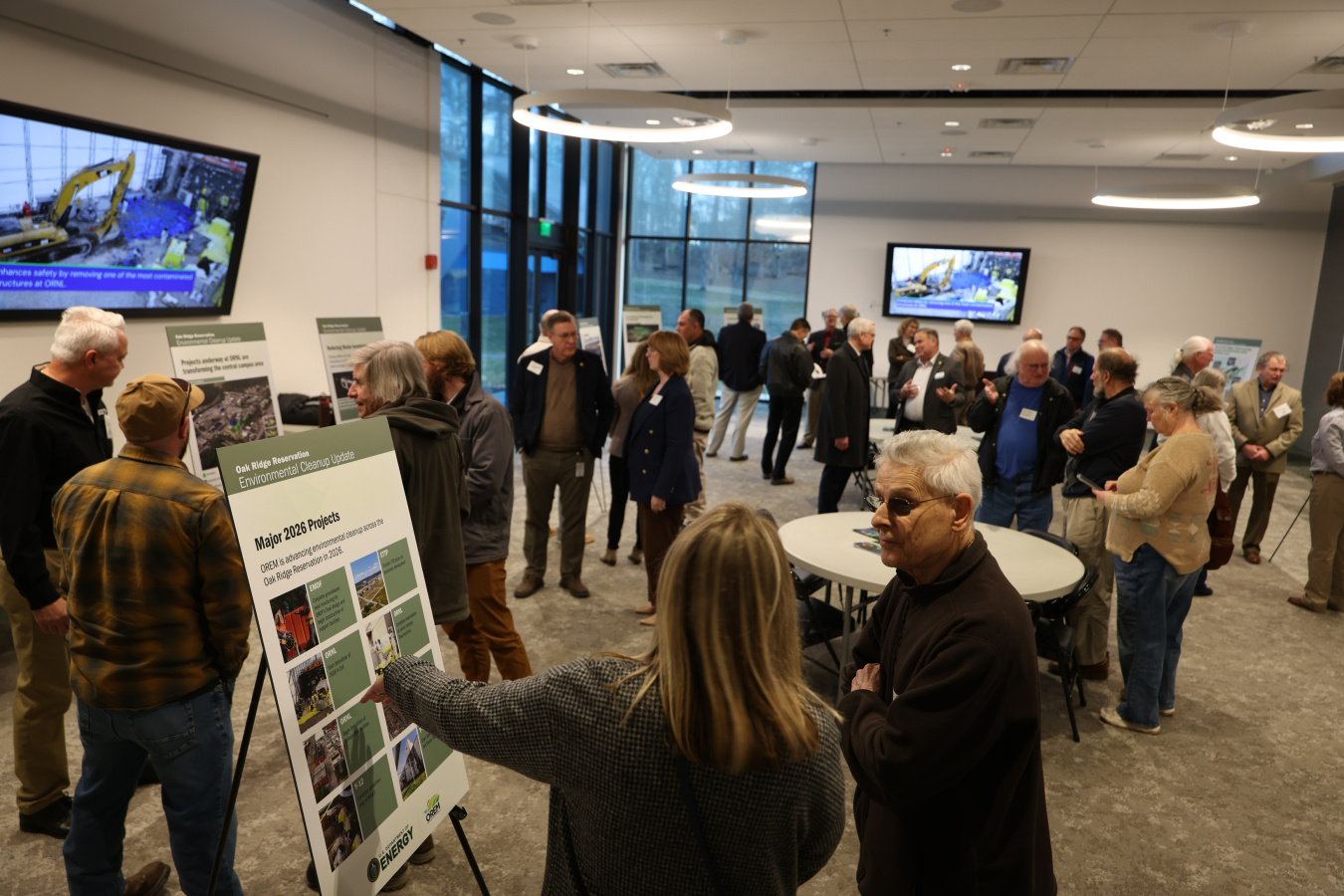 A room full of people looking at posters across the room at a public meeting