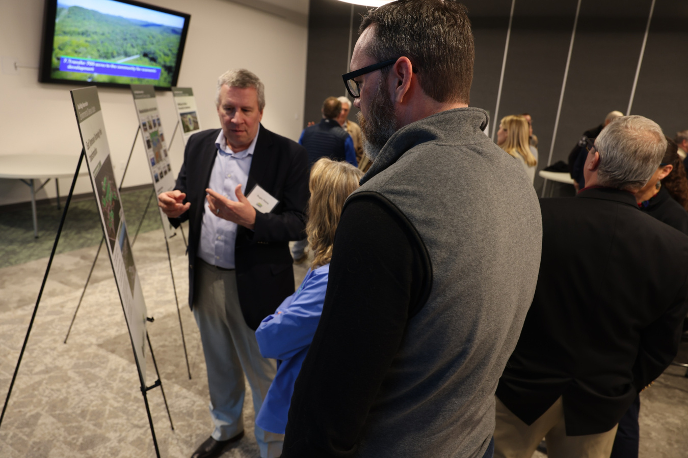 A man speaking about a poster displayed in front of him at a public meeting