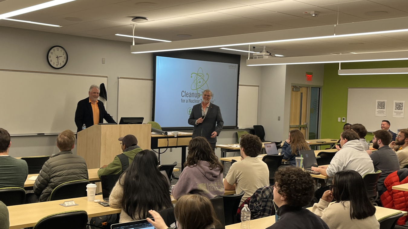 Two professionals standing at the front of a room giving a presentation to a crowd