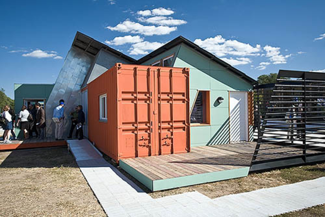 Exterior of the Colorado team's Build Challenge house, showing a smaller square section in front of other sections with peaked roofs, and a walkway in front of the structure.