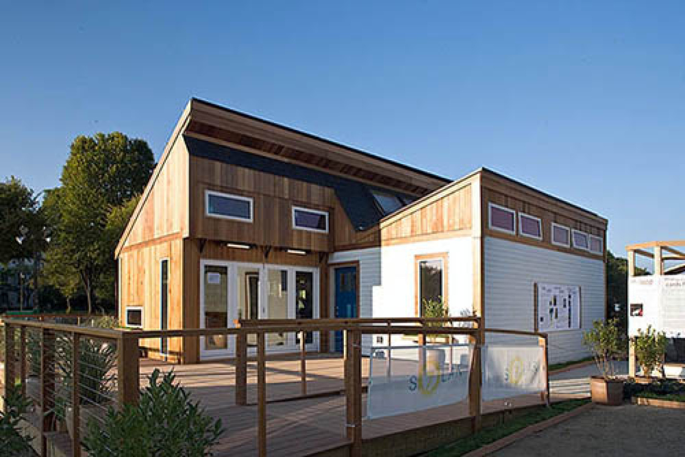 Exterior of the Massachusetts team's Build Challenge house, showing a larger section with a small section in front of it, a slanted roof on each section, and several small windows along the top of each, and several longer windows near the ground.