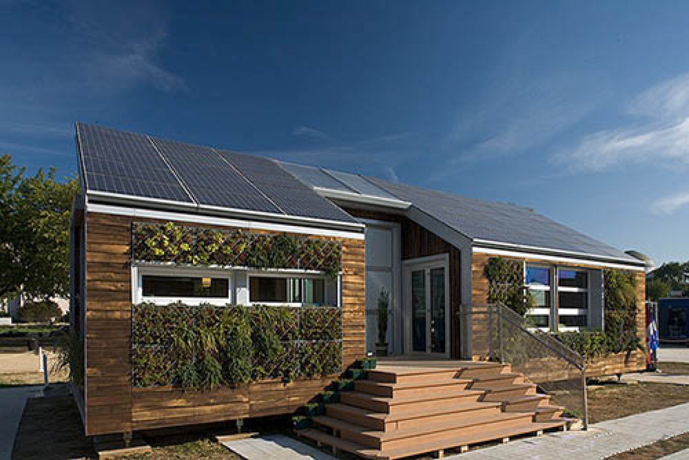 Exterior of Team Montreal's Build Challenge house, showing solar panels encompassing the slated roof and pyramid-shaped staircase leading to the front door.