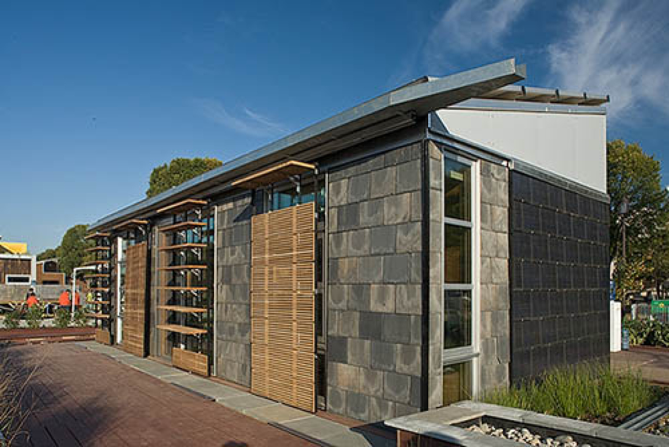 Exterior of the Penn State team's Build Challenge house, showing various sections along the front of different materials that appear to be stone or wood.