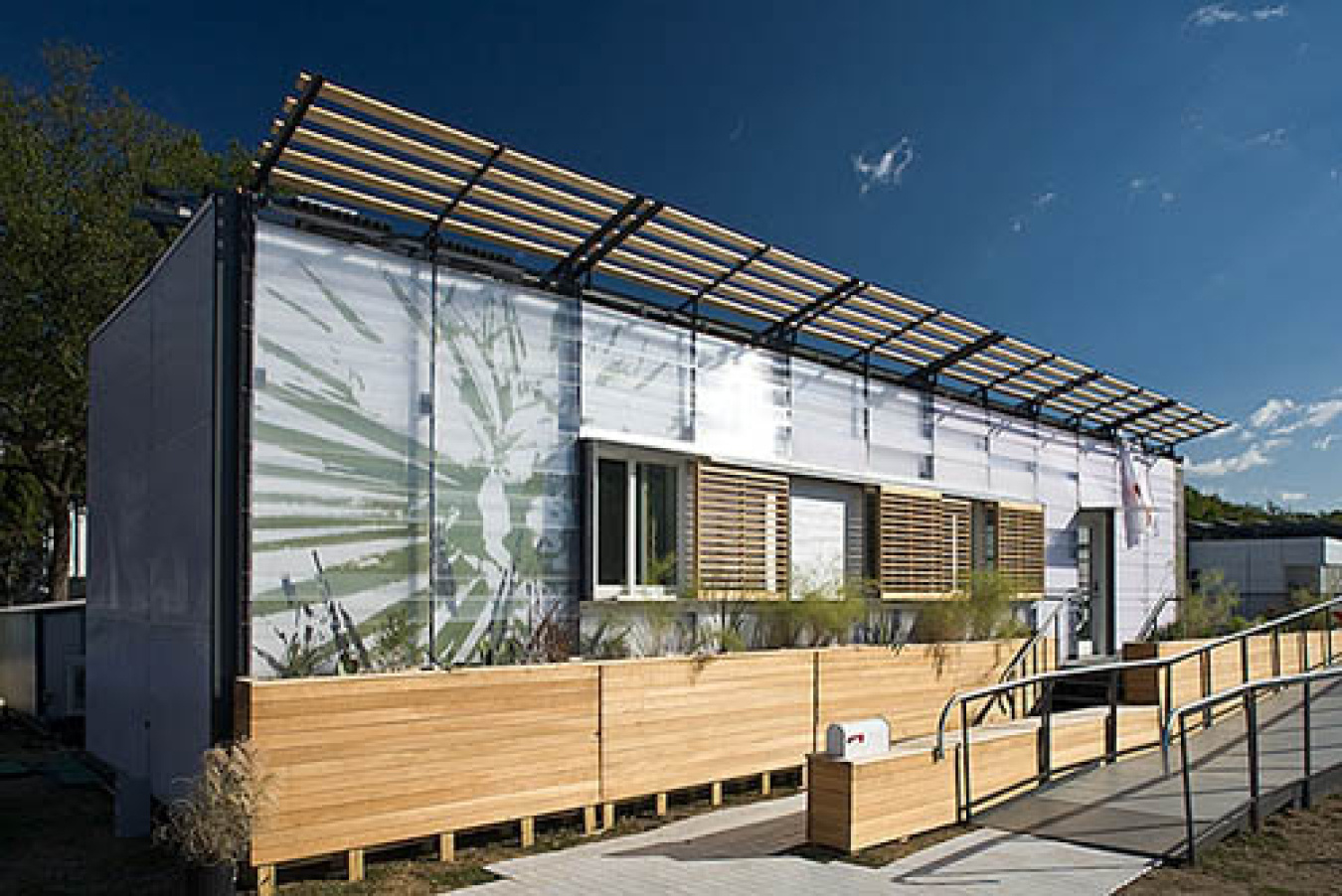 Exterior of the University of Texas - Austin team's Build Challenge house, showing the various panels and windows along the front, and a ramped walkway along the front.