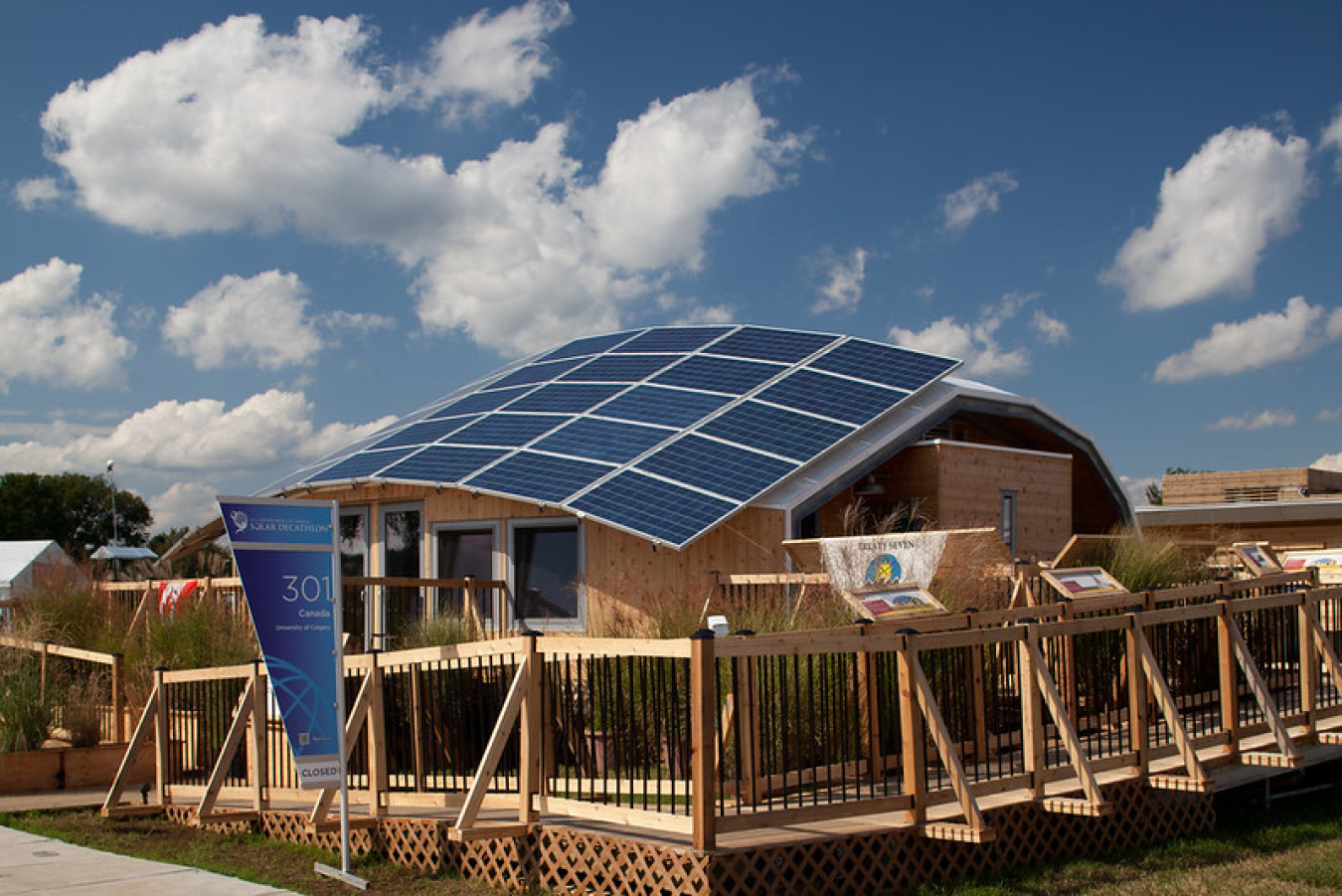 Exterior of Team Canada's Build Challenge house, showing a large array of solar panels comprising the roof, and a ramped wooden walkway around the structure.