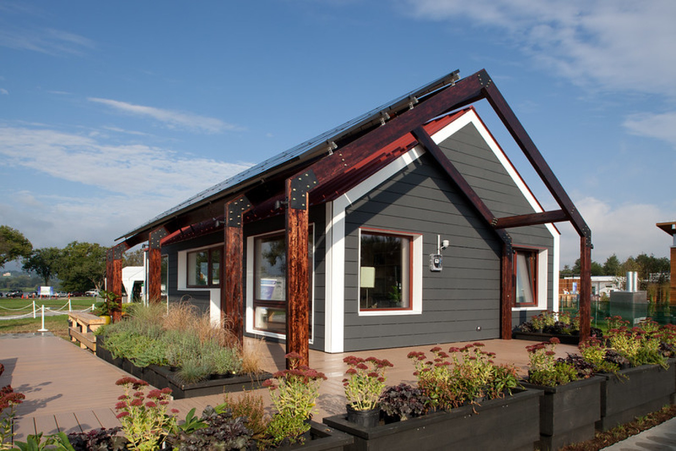 Exterior of Team Massachusetts' Build Challenge house, showing a sloped roof with framework around it, and landscaping around the structure.