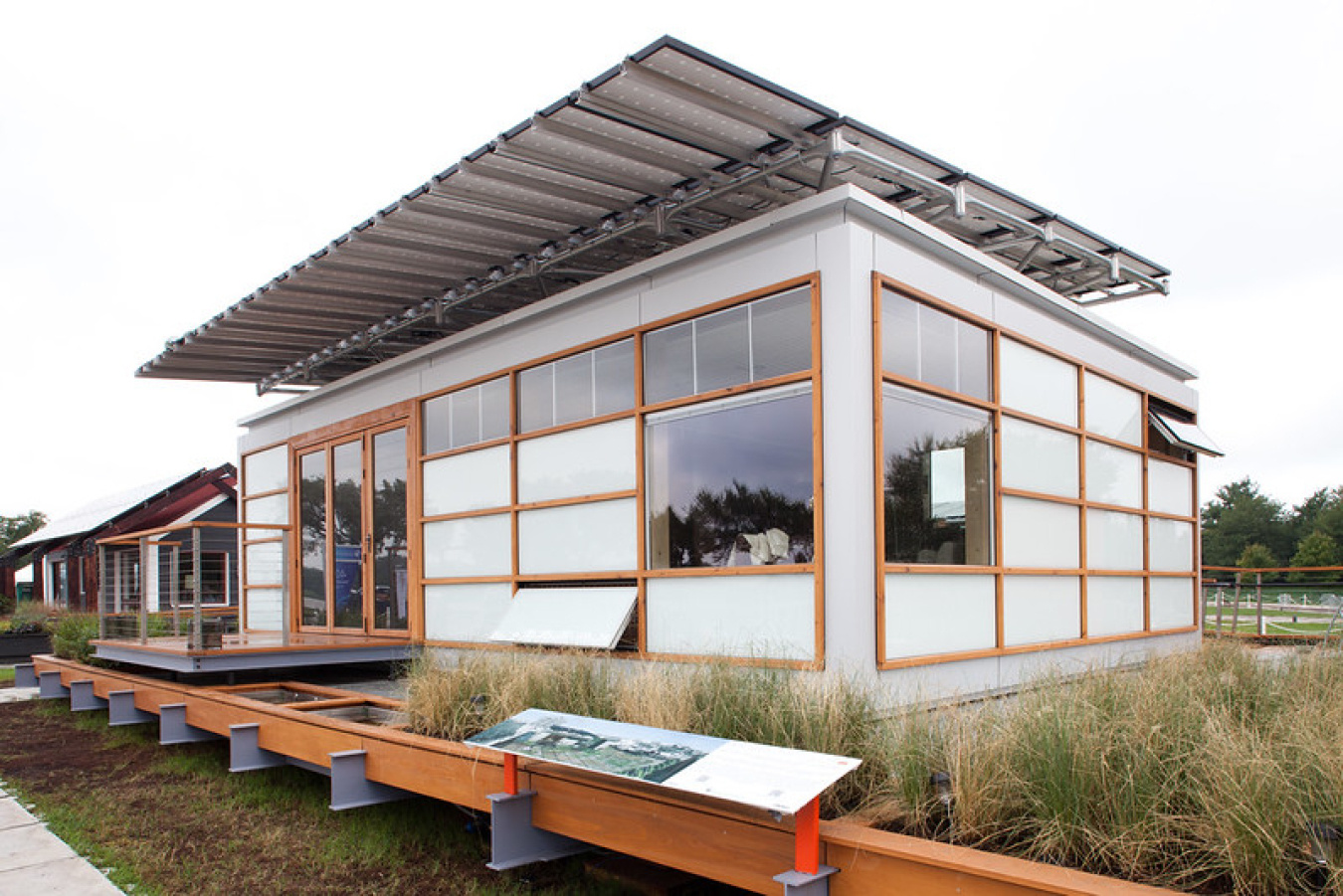 Exterior of Team New York's Build Challenge house, a square structure with lots of windows and panels with a contrasting trim.