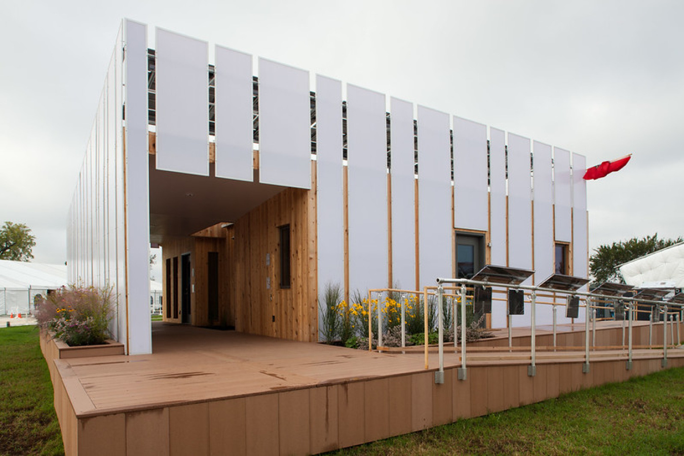Exterior of the Ohio State team's Build Challenge house, showing a series of large slats across the front, with an alcove and entrance on the left side, and a porch and wheelchair ramp leading off the other side of the house.