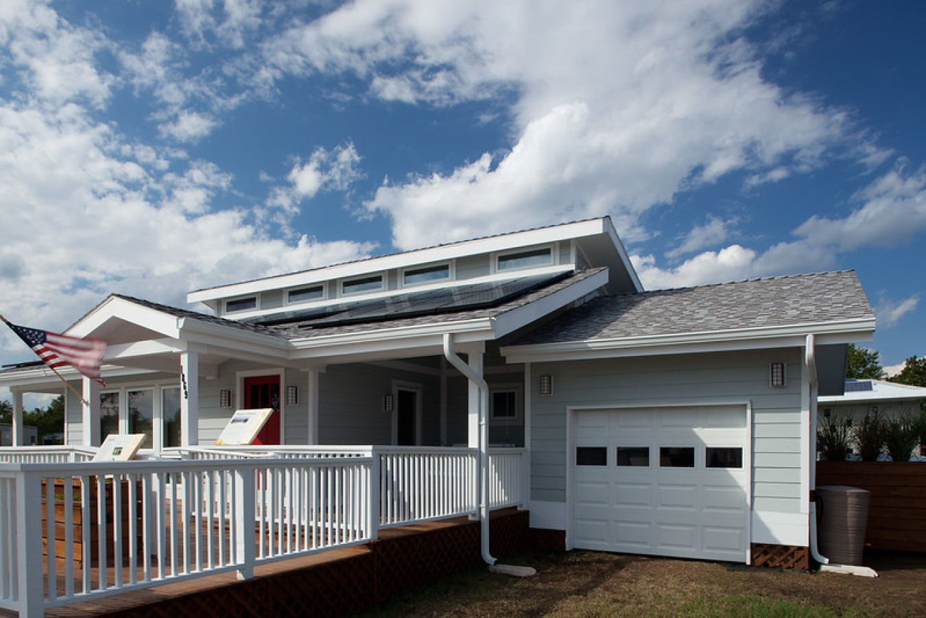 Exterior of the Purdue team's Build Challenge house, with small columns in front of the front door, a gated sidewalk leading up to it, and a small garage door on the right side of the structure.