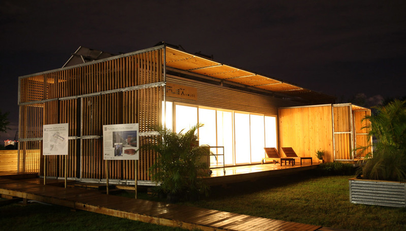 Exterior of Team Florida's Build Challenge house at night, showing a windowed front, faced off at an angle from the camera, with a fully lit interior.