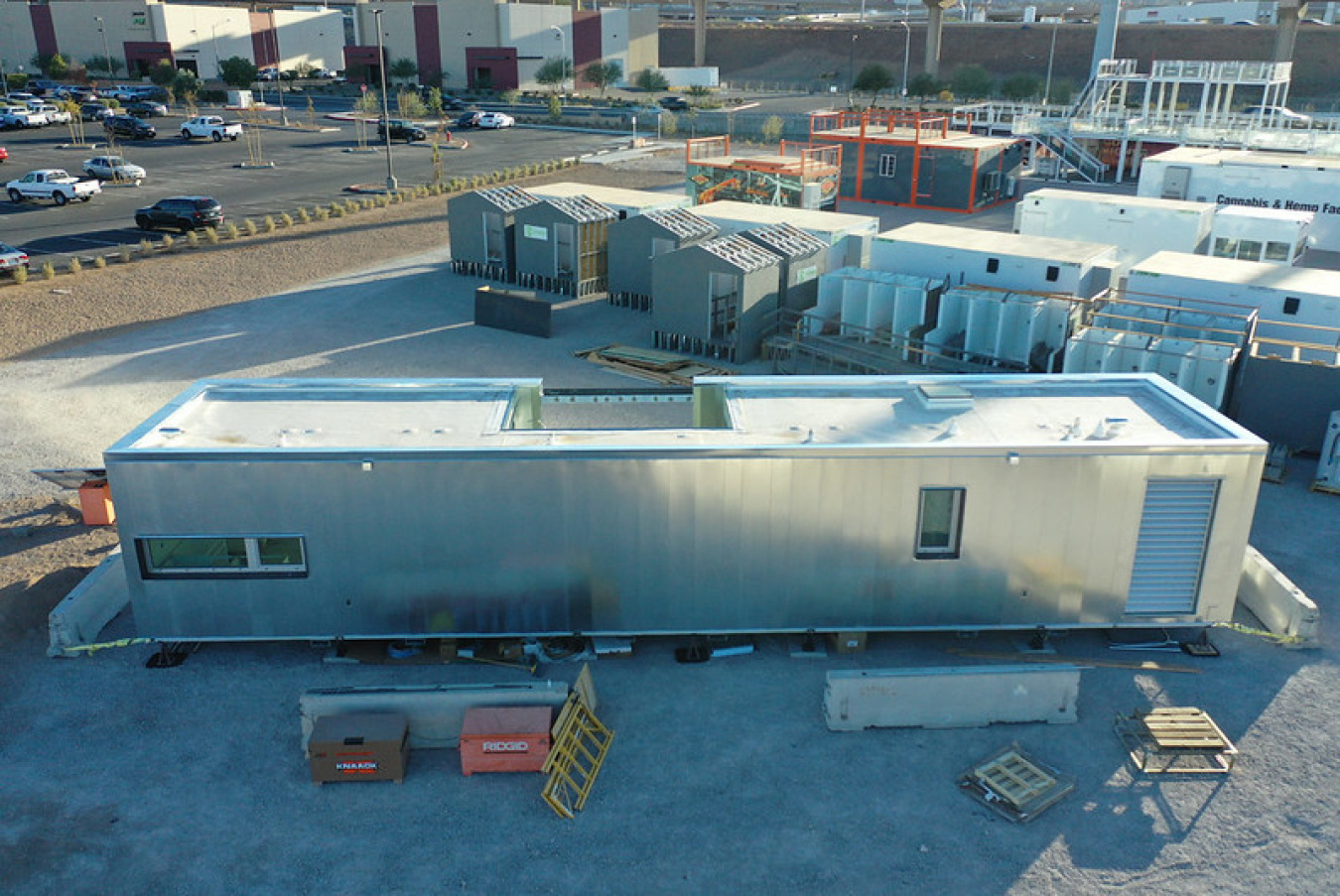 Overhead shot of the Las Vegas team's Build Challenge house construction site, showing a long rectangular building with few windows and some supplies sitting near it.