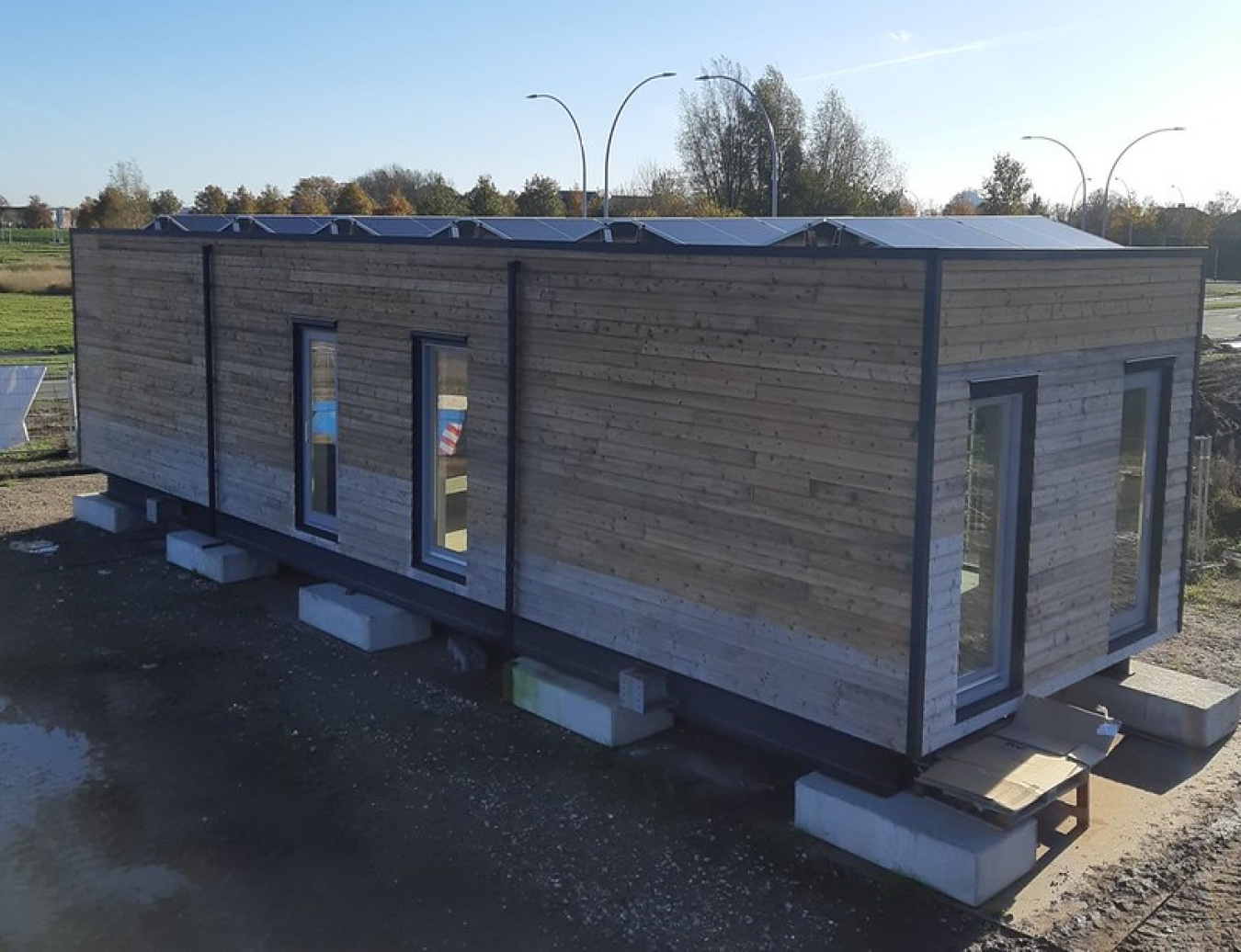 Exterior of the Netherlands team's Build Challenge house, in a rectangular shape with two windows on two sides, set up on blocks.