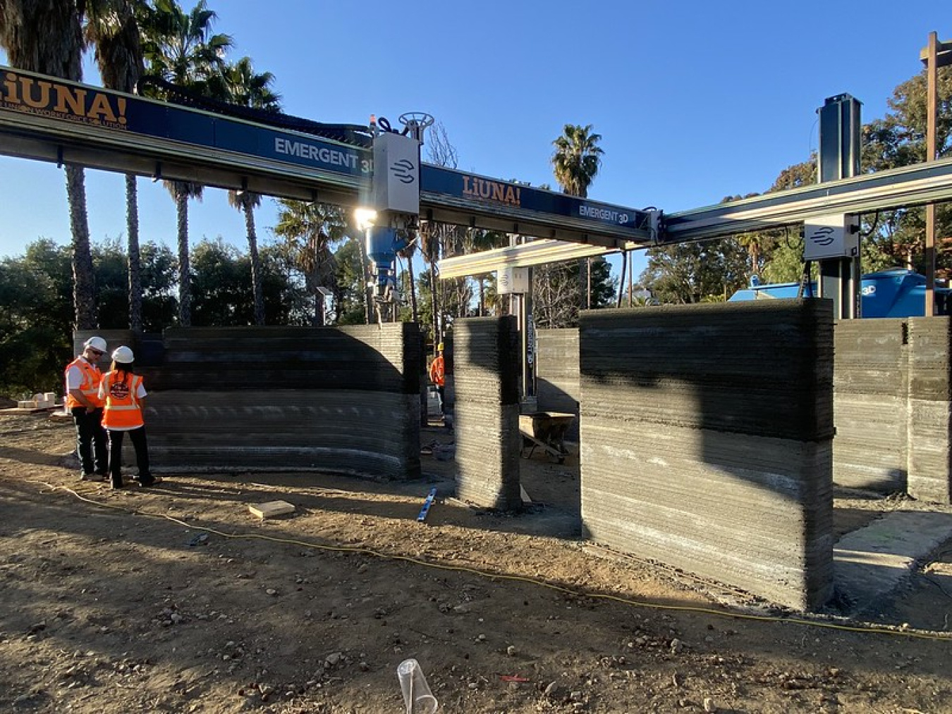 The construction site for the 2023 Build Challenge team from Woodbury University, showing two people in construction vests standing next to part of a structure.
