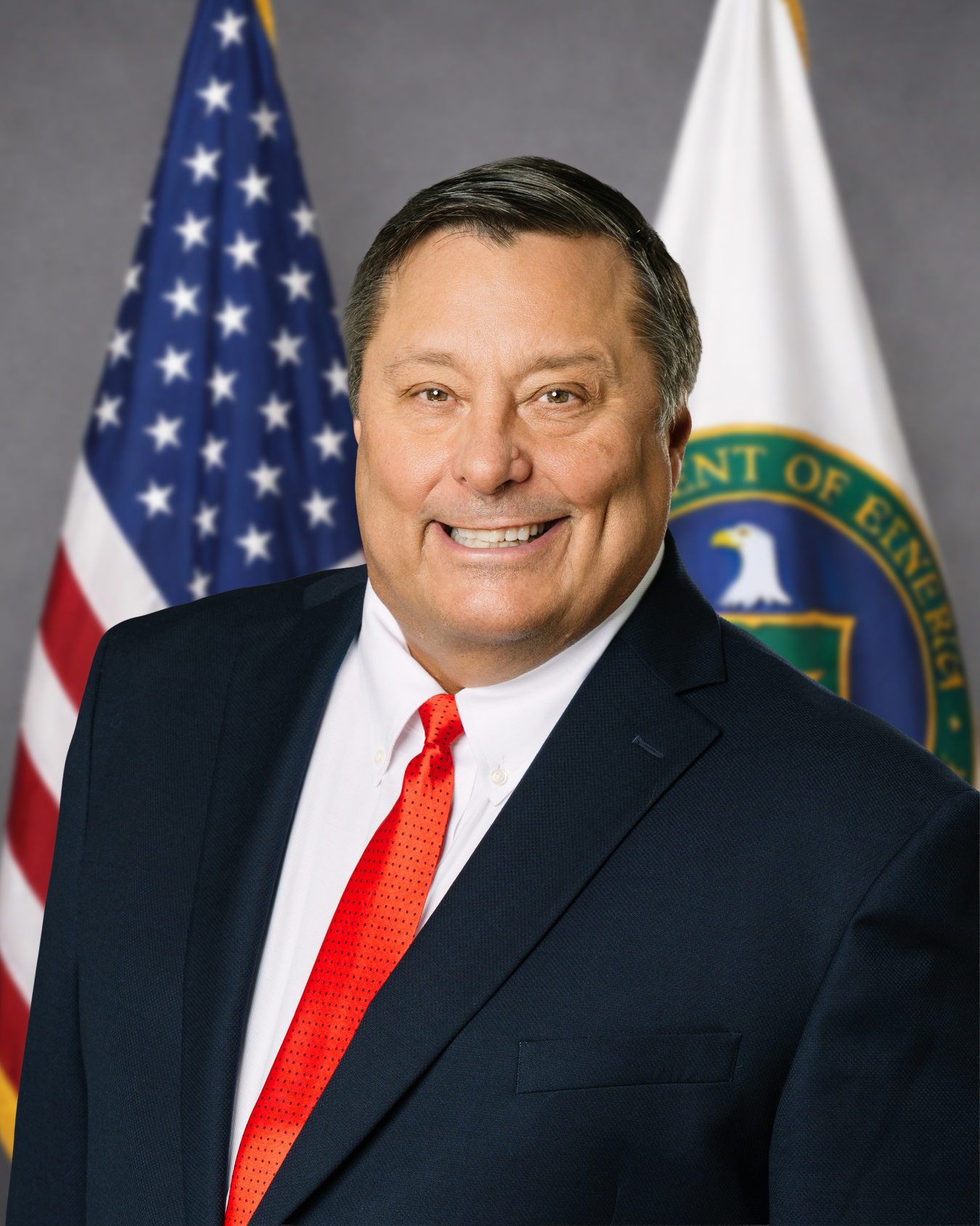 Man in a suit posing for a professional photo in front of the American flag