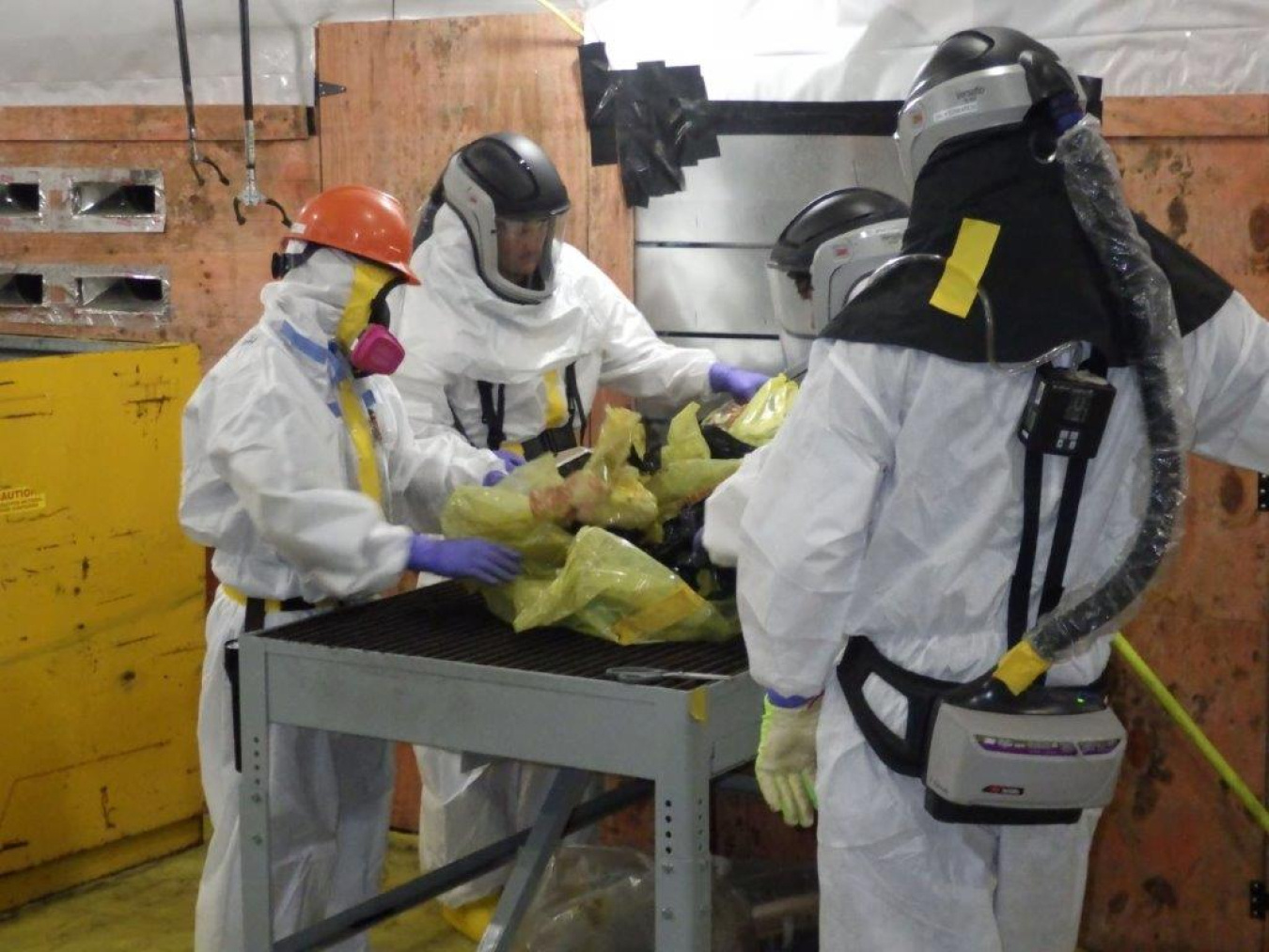 A group of employees in hazmat gear sanitizing materials at the Oak Ridge Site
