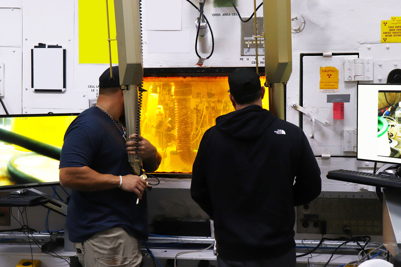 Two employees operating a hot cell box