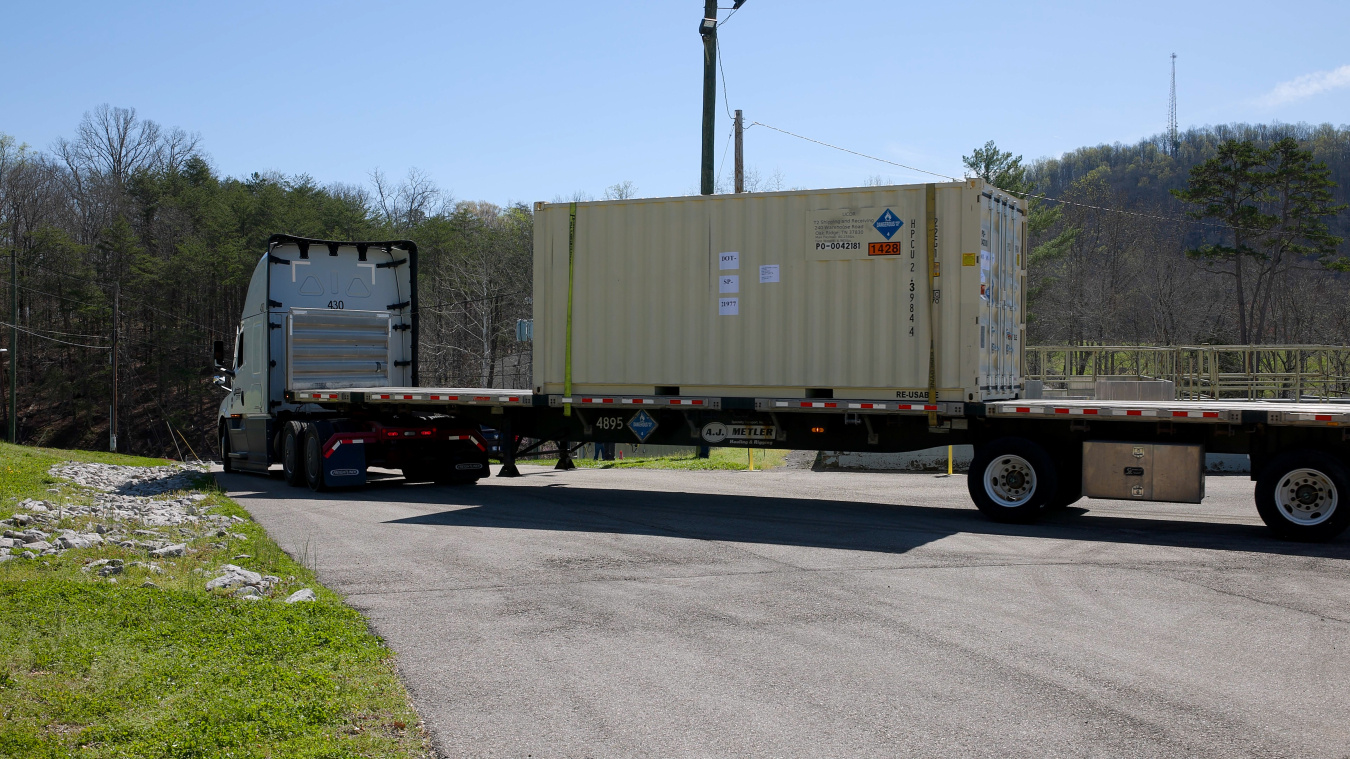 A large shipping container on the back of a tractor trailer truck