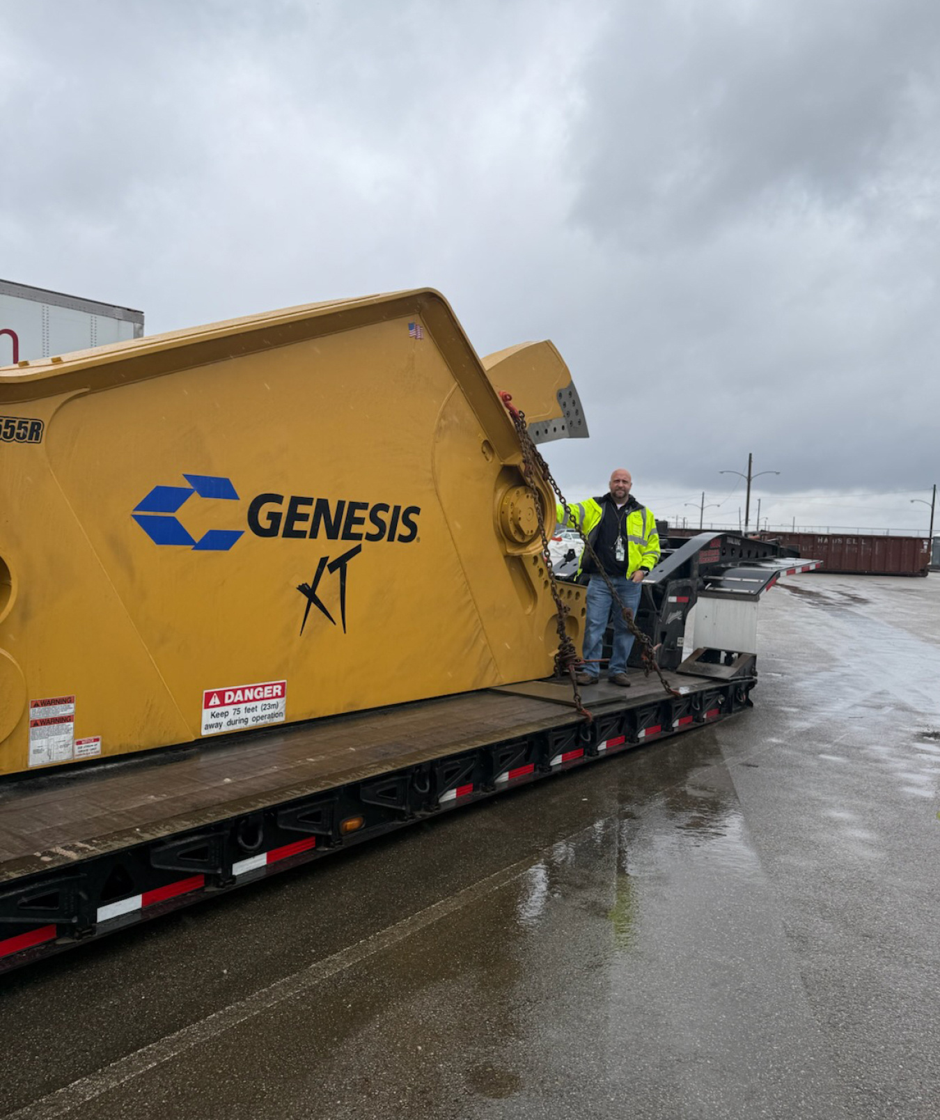 A large yellow package with the words "Genesis" on the side and man standing in front