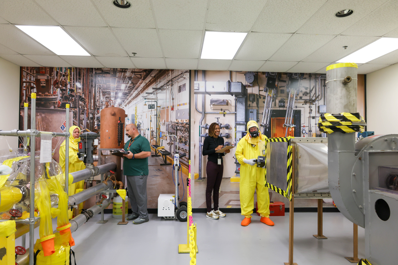 Employees in protective gear working on safety mockups