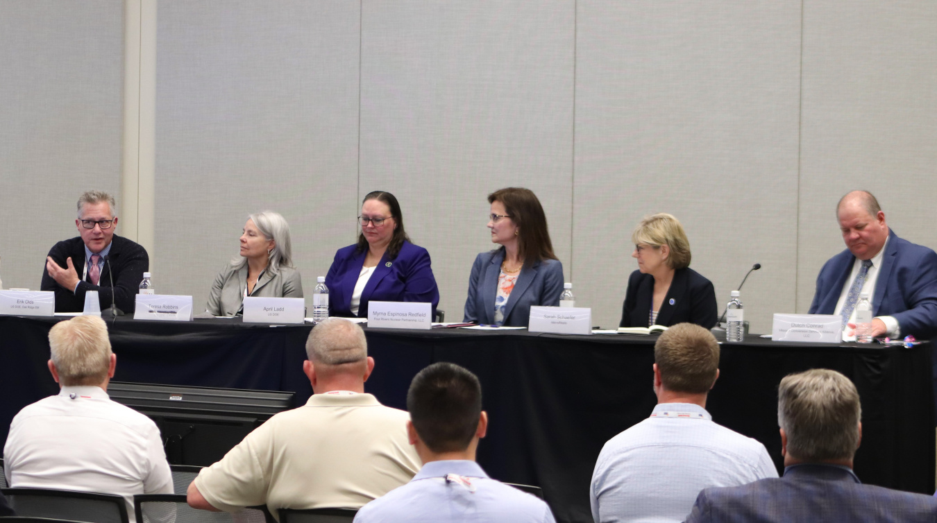 A group of professionals sitting on stage participating in a panel at a conference
