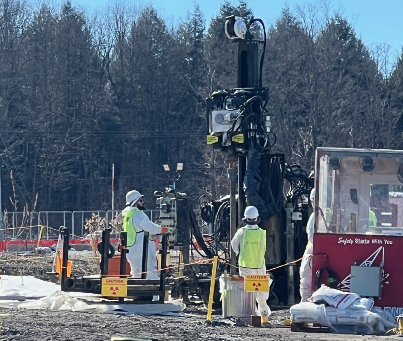 Employees in protective gear standing beside a groundwater sampling machine
