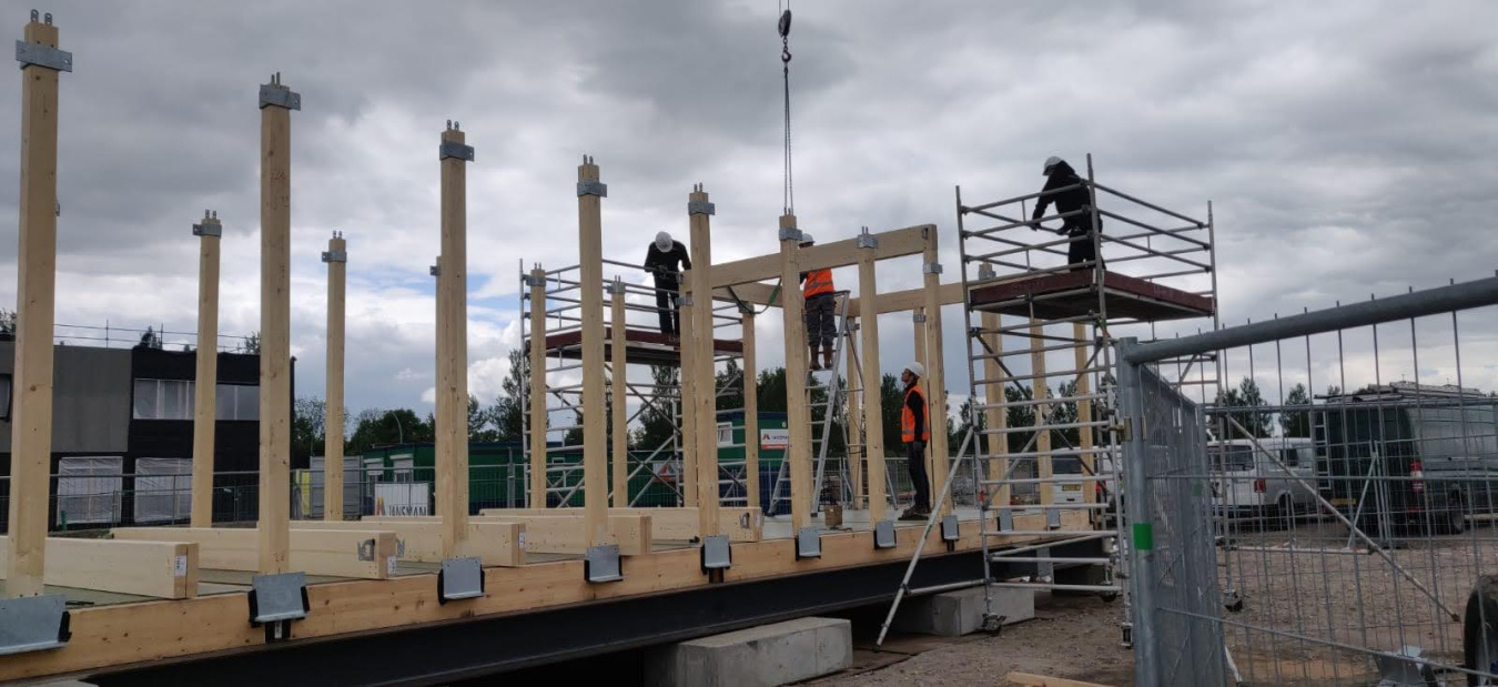 Two people in hard hats working at the construction site of a Build Challenge competition house.