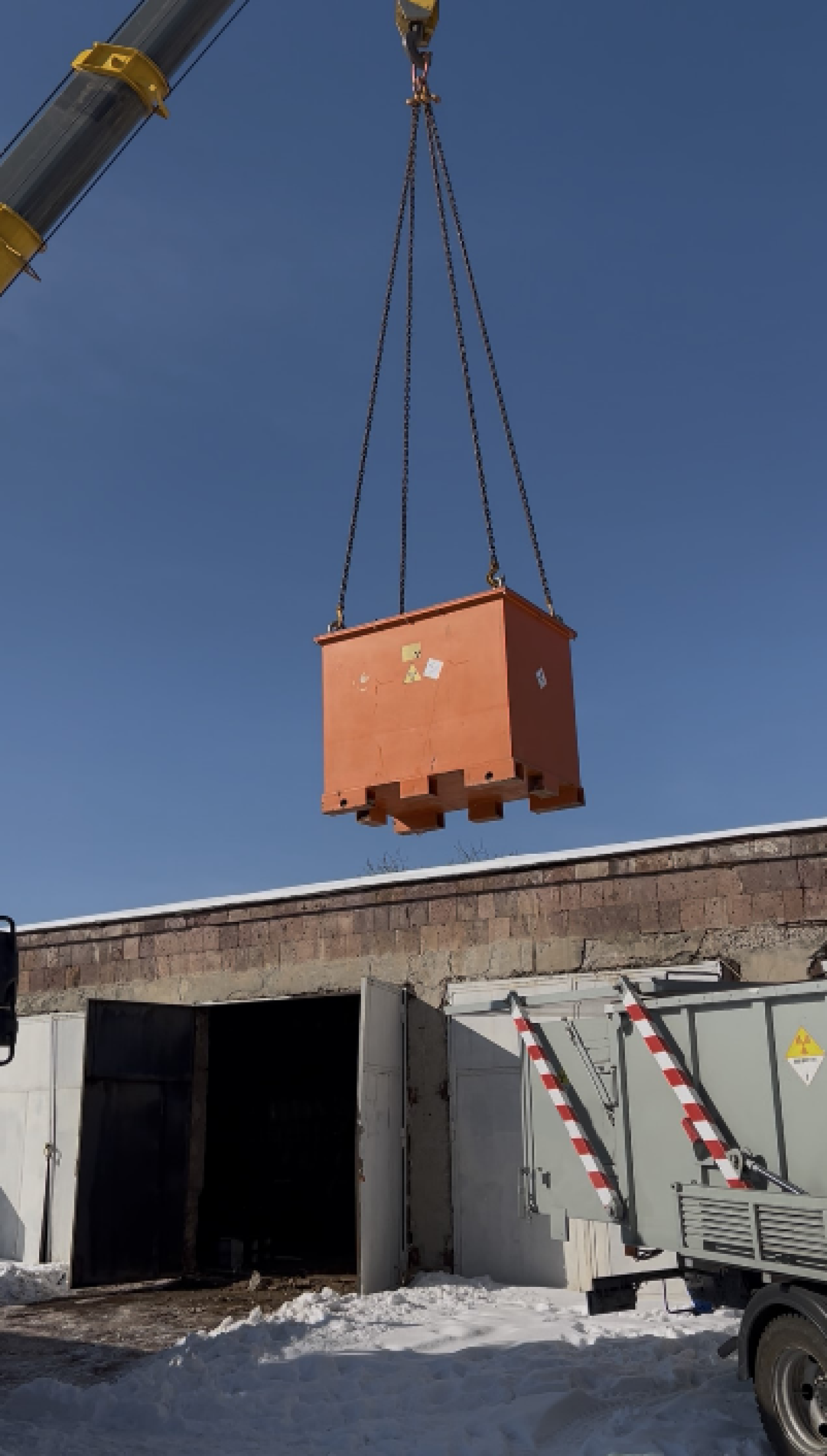 A crane suspends a small shipping container in the air.