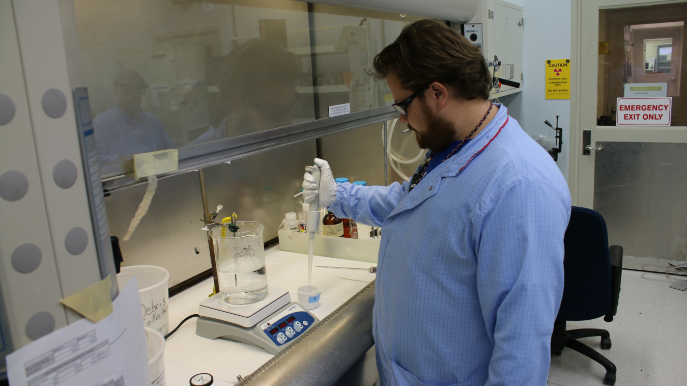 A scientist in a blue lab jacket working in a lab at the Hanford Site