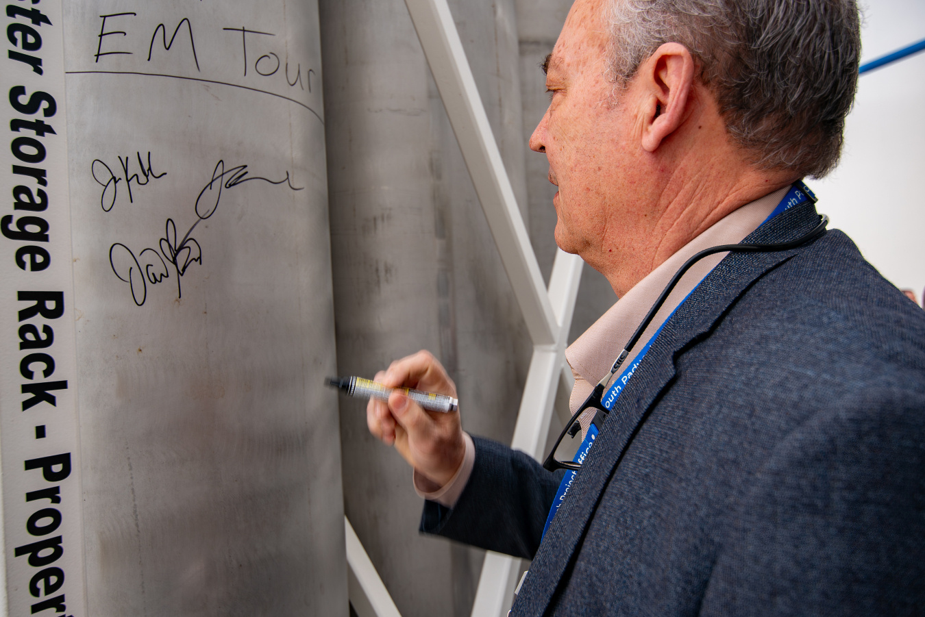 An EM leadership member signing his name on a metal cask at the Idaho Site
