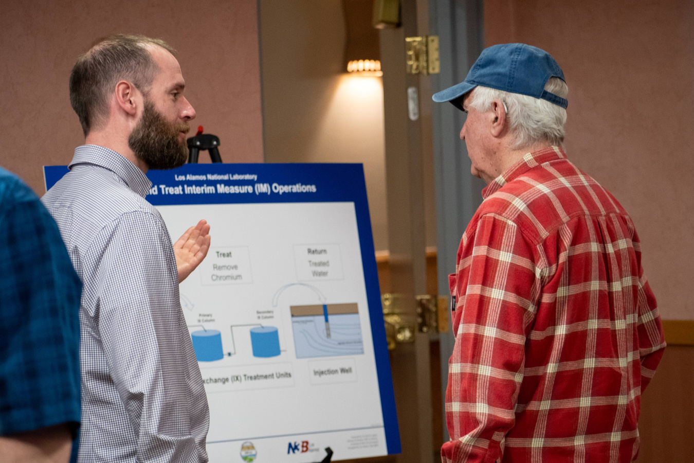 Two men talking to each other standing by a posterboard at a forum event