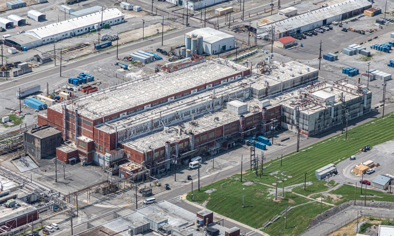 An aerial view of a large brick facility building at the Oak Ridge Site