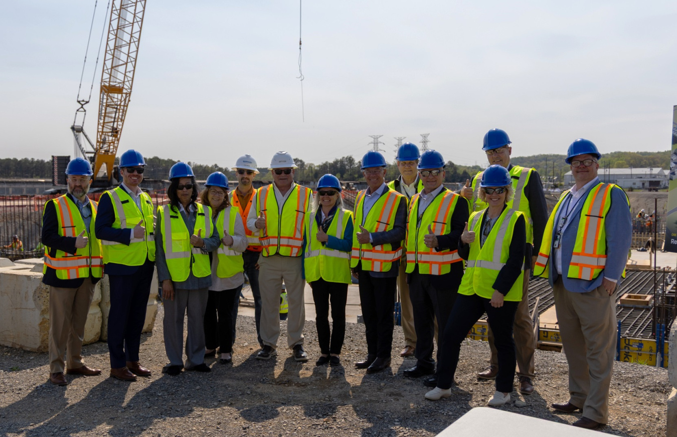A group photo of professionals in yellow safety vests and hard hats posing for a picture