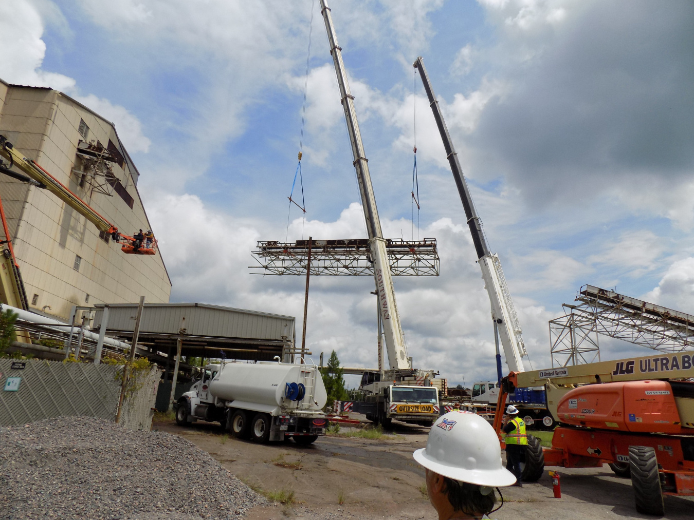Two large while construction vehicles beside a large facility building at the Savannah River Site