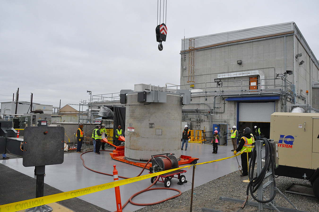 Workers gather to guide a crane hook down to its target. 