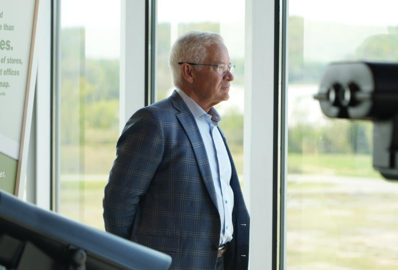 A man in a suit looking out a window at the Oak Ridge Site