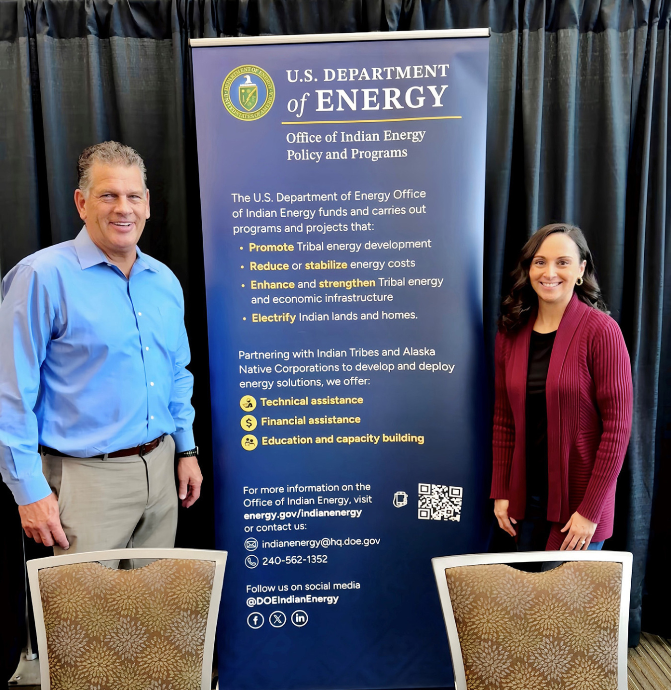 Two people standing next to a banner.