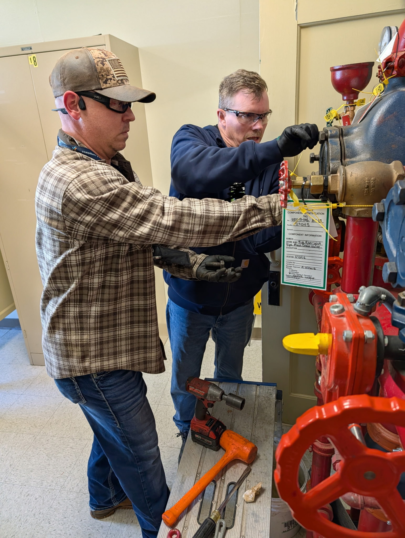 Two employees working on a red pipe valve at the Hanford Site