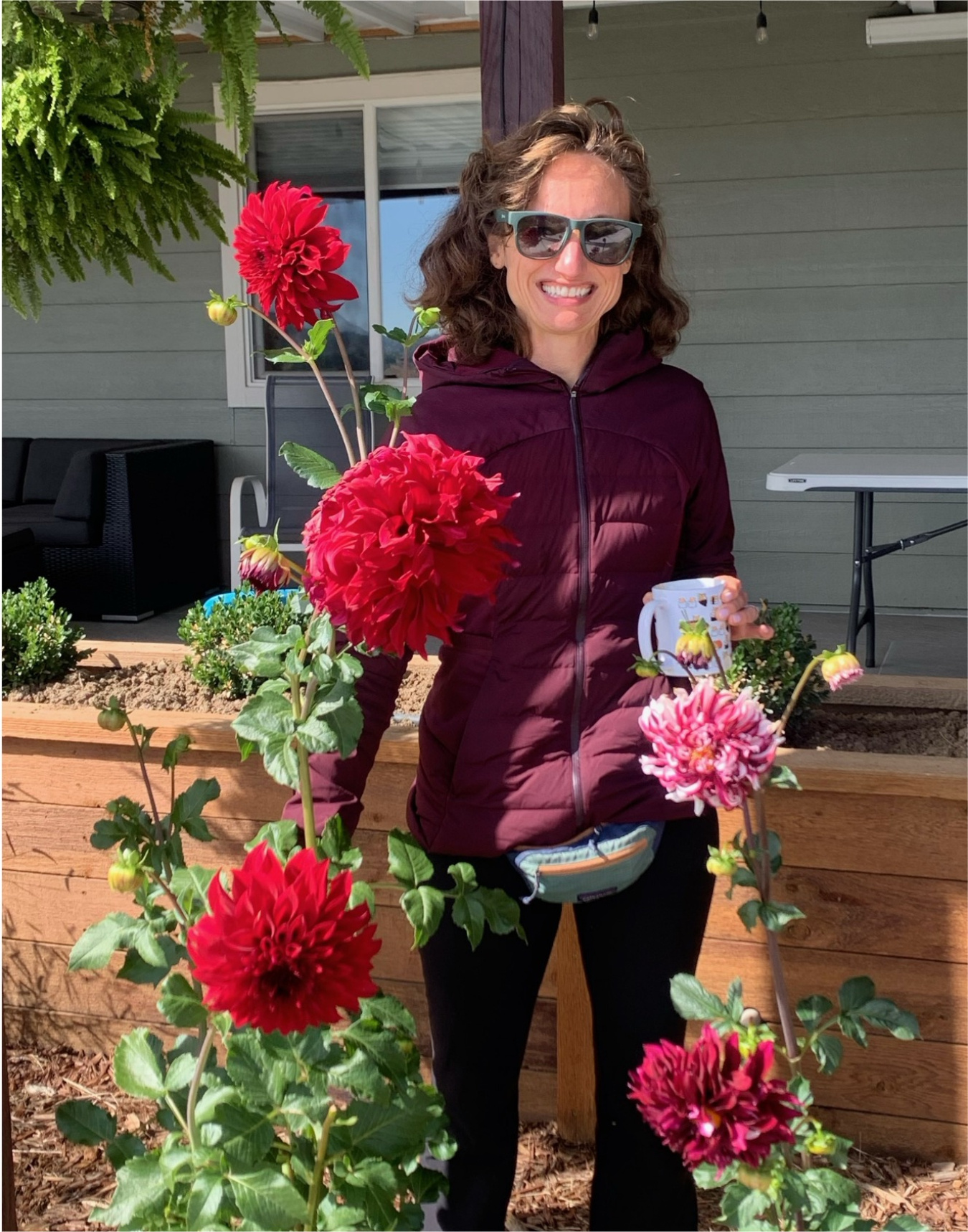 H2O Director Nichole Fitzgerald holding dahlia flowers in a garden bed