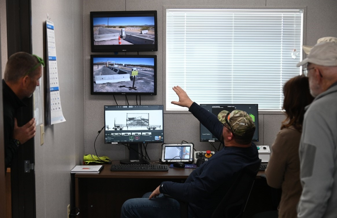 A group of employees in a control room looking at multiple different screens