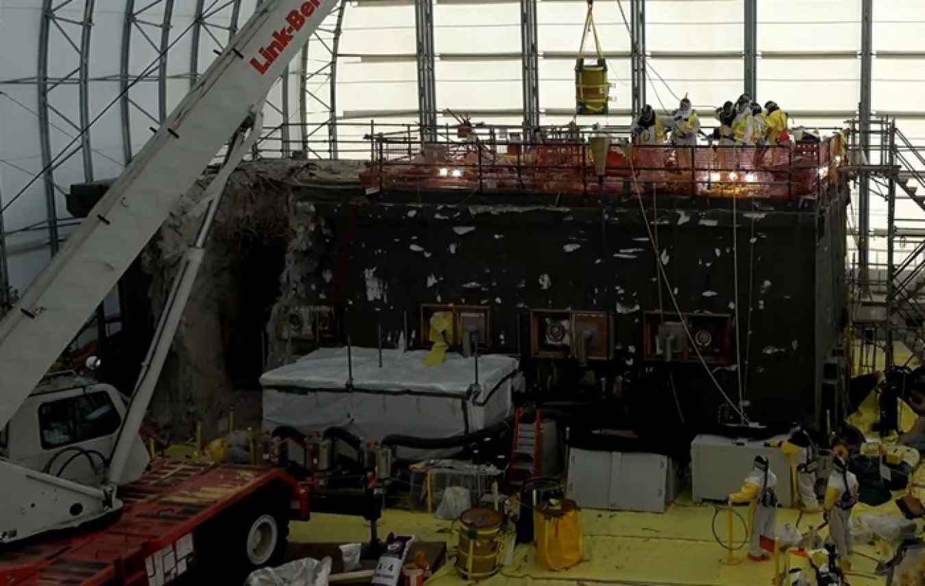 Employees in safety gear working to remove waste drums from a laboratory building