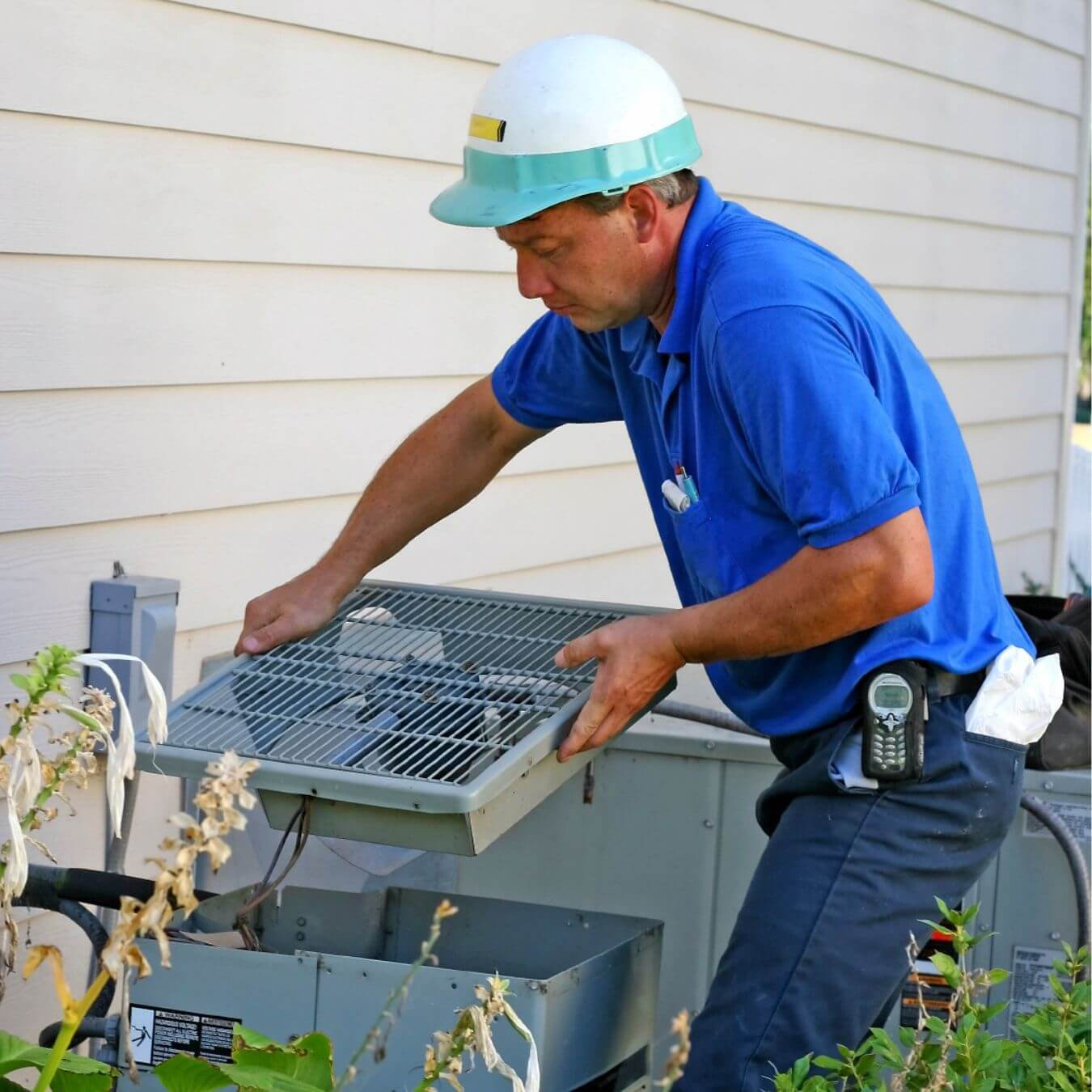 A worker doing maintenance on an air conditioner