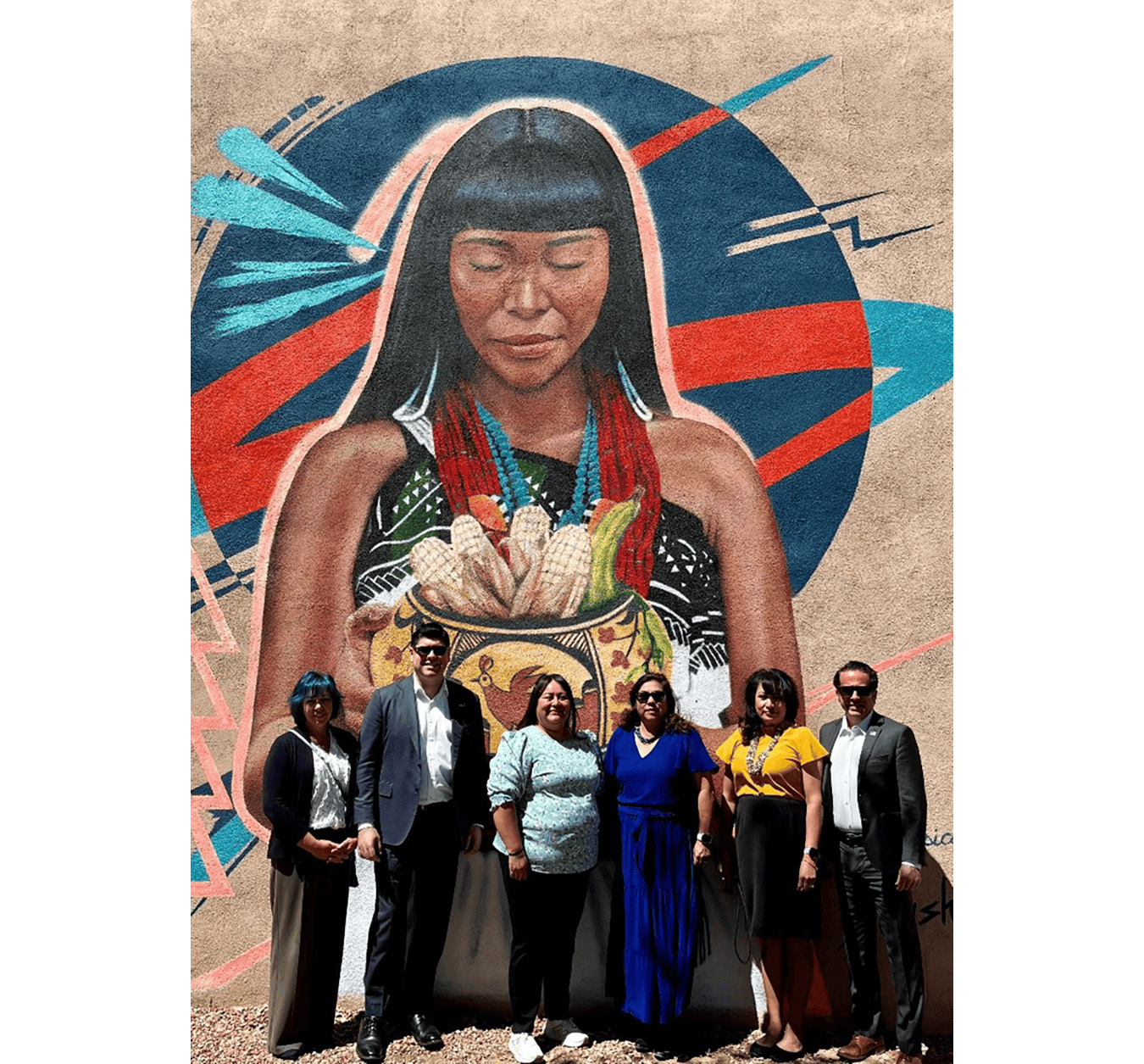 Group stands in front of mural