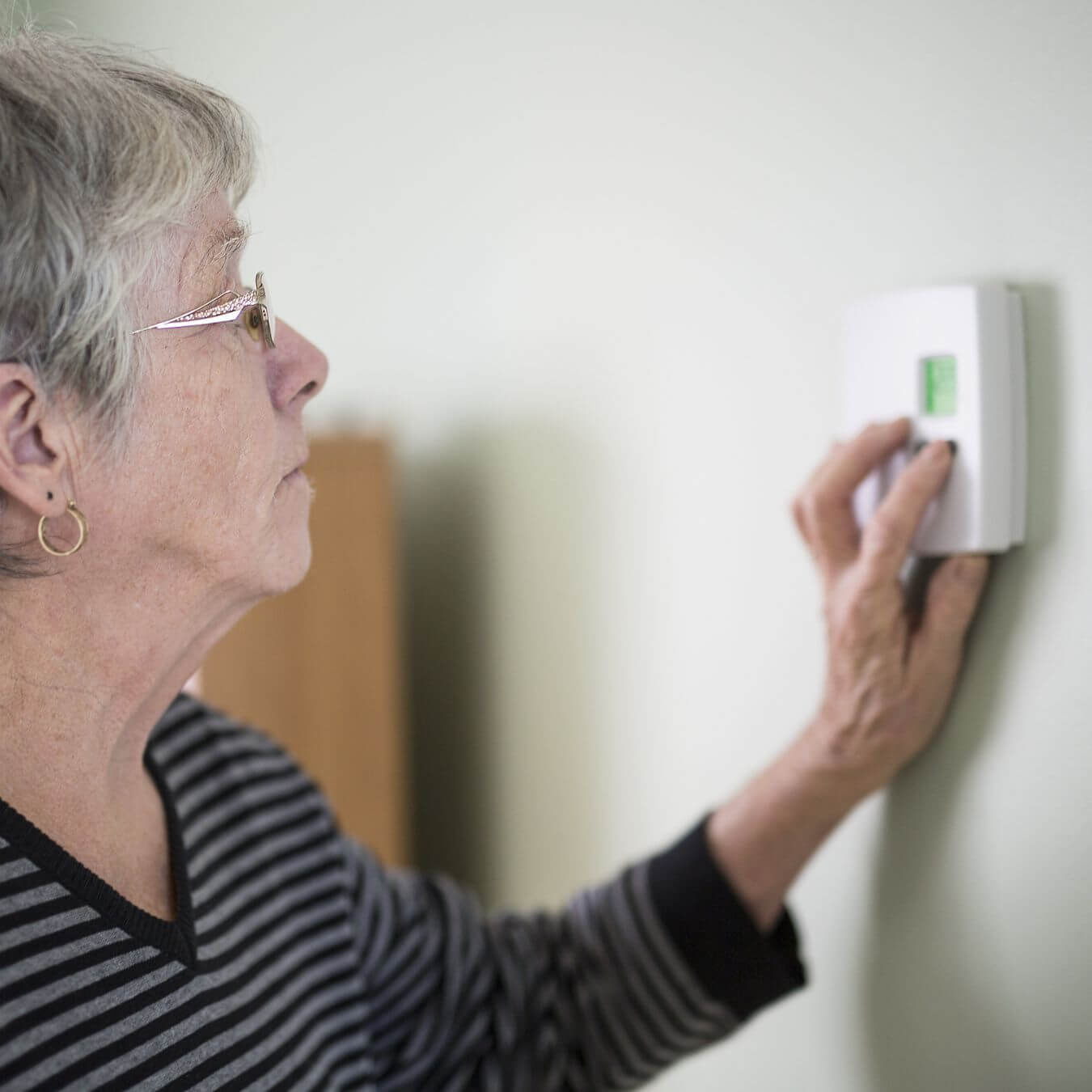 A woman setting a thermostat