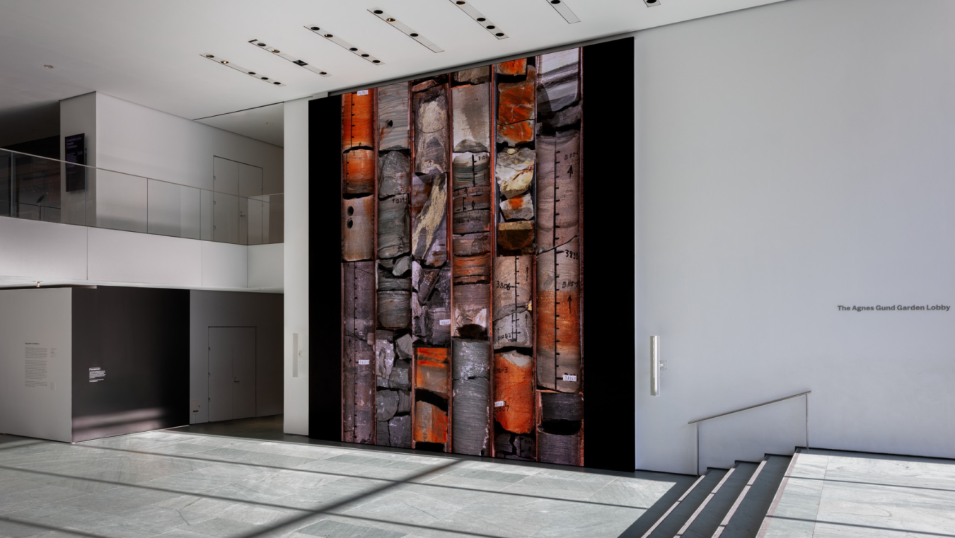 Photo of an art installation placing renderings of core samples in six columns, running from the floor to the ceiling of a musuem space.