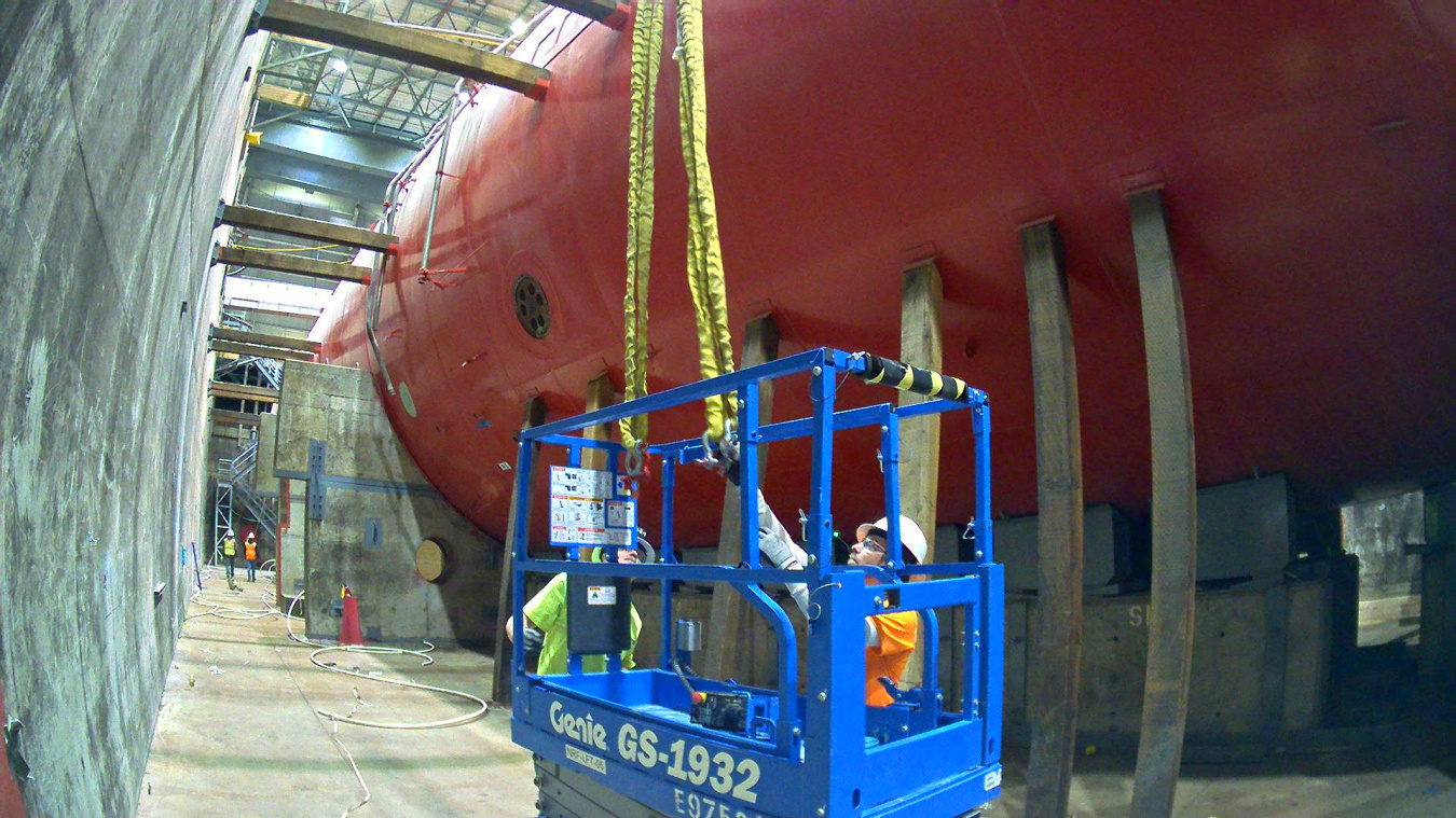 Employees in a blue lift working on a large red submarine at the Idaho Site