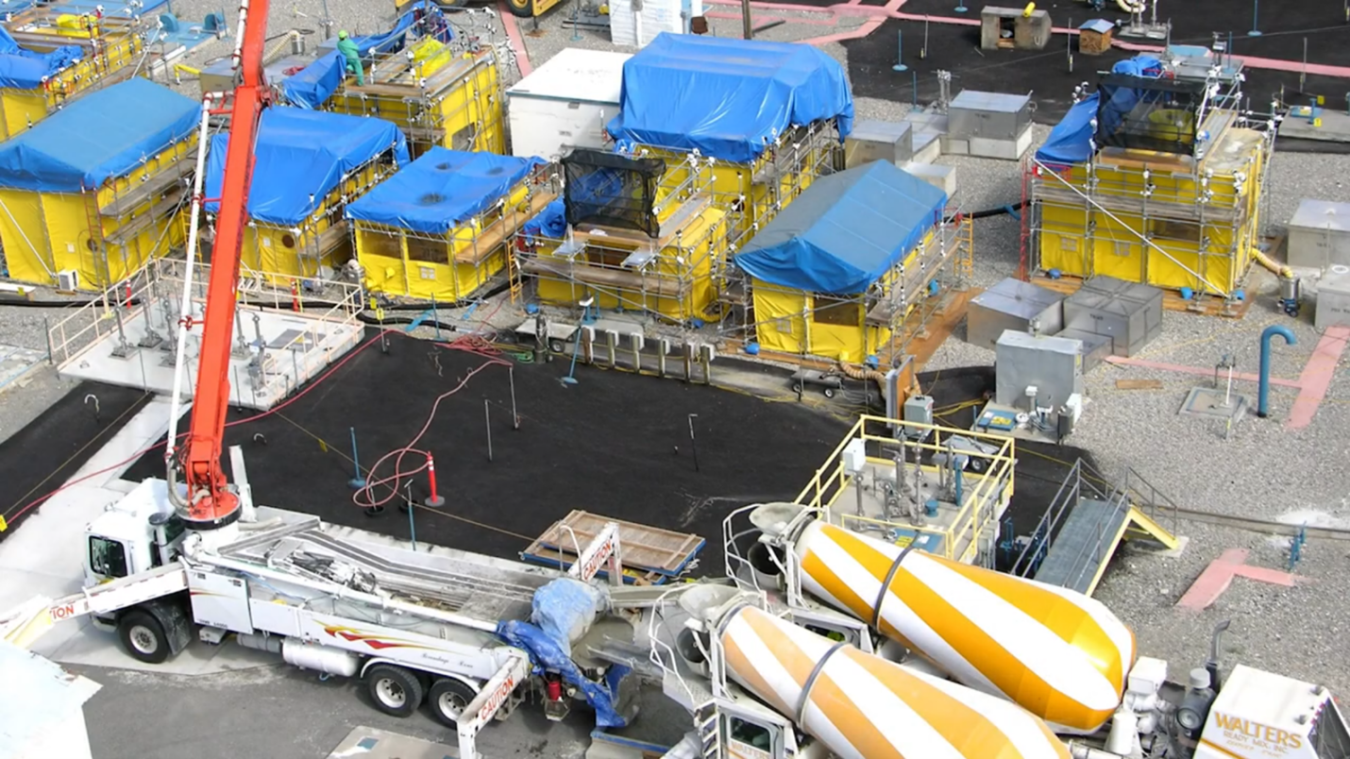 Aerial view of a tank fark with yellow and blue tents and multiple construction vehicles